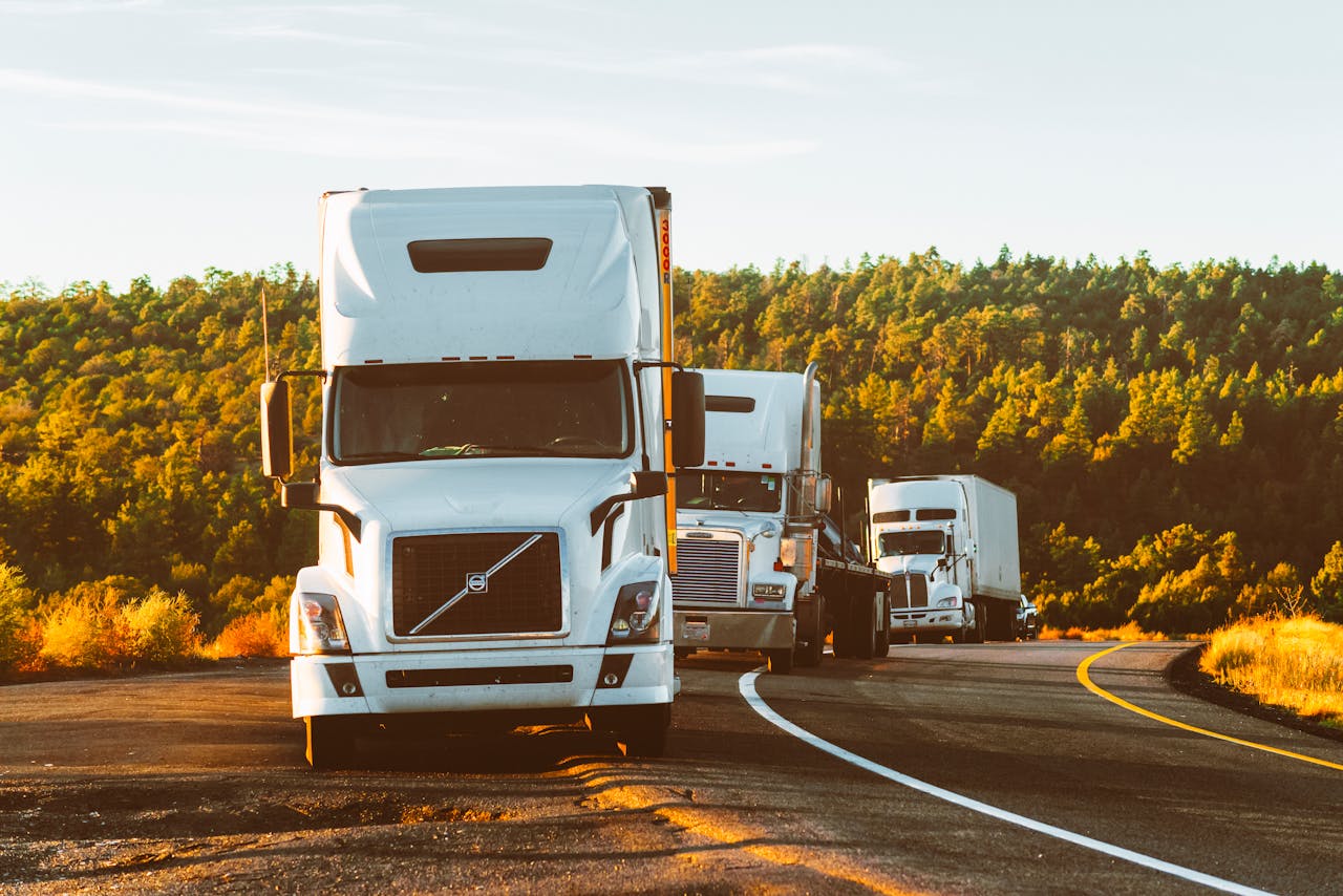 hero-img-01 Three semi trucks driving on a highway through a forested landscape in Arizona.